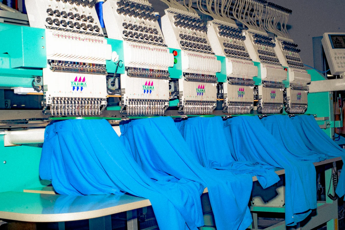 Industrial embroidery machines working on bright blue garments.
