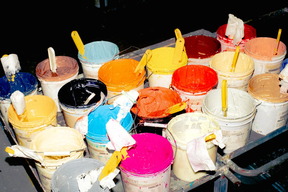 Open buckets of colorful printing pigments in a production workspace.