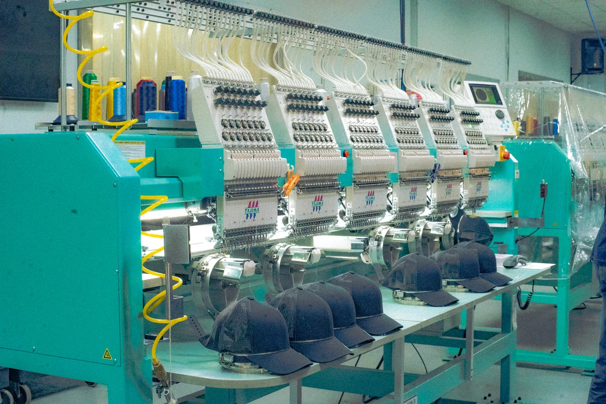 A bank of embroidery machine heads with dark caps held in work fixtures.