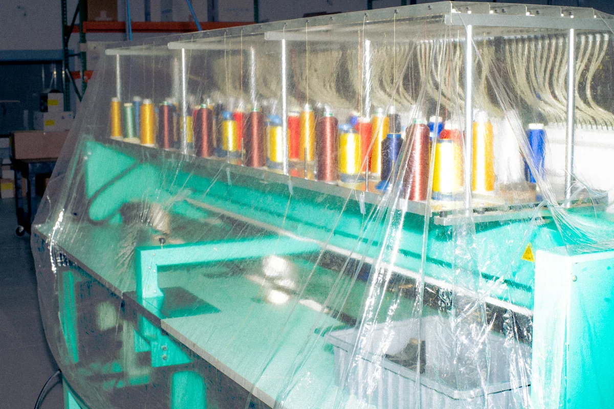 Production floor through curtain. Editorial illustration of embroidery / working environment.
