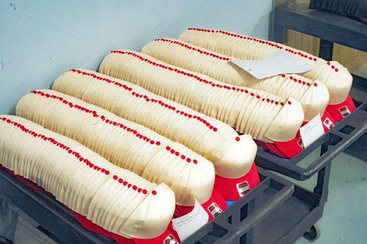 Blank caps staged for processing. Editorial illustration of production staging / undecorated inputs.