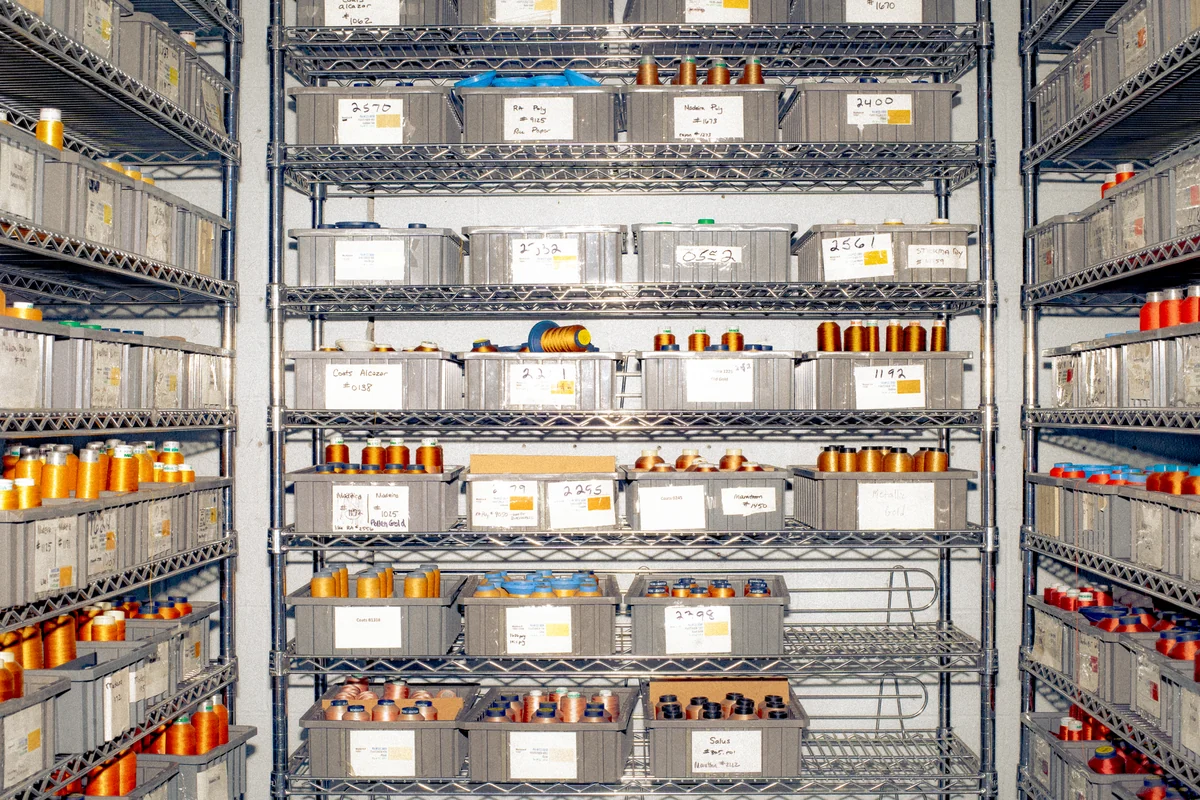 An aisle between shelves of thread cones used as production materials.